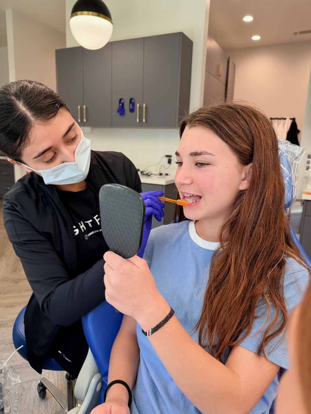 Team member showing a patient their new braces in a hand mirror